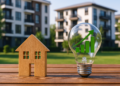 Modello di casa in legno e lampadina con grafico verde che simboleggiano l’efficienza energetica immobiliare e l’aumento del valore degli investimenti