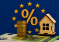 Moneta da un euro, casa in miniatura e bandiera UE con simbolo percentuale – concetto di taglio tassi BCE giugno 2025