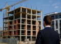 Vista di una casa in costruzione con gru accanto a un palazzo moderno completato
