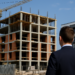 Vista di una casa in costruzione con gru accanto a un palazzo moderno completato
