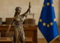 Statua di Lady Justice con bilancia e spada davanti alla bandiera dell’Unione Europea, simbolo del diritto di proprietà