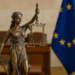 Statua di Lady Justice con bilancia e spada davanti alla bandiera dell’Unione Europea, simbolo del diritto di proprietà
