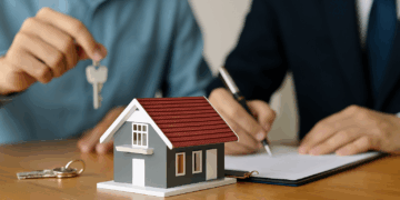 Due persone firmano un contratto immobiliare con un modellino di casa e chiavi sul tavolo, concetto legato al decreto Salva Casa