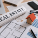 Scrivania con giornale, laptop e modello di casa in legno per notizie immobiliari settimanali