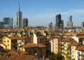 Affitti Milano, panorama con tetti in cotto e grattacieli moderni sotto un cielo azzurro