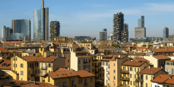 Affitti Milano, panorama con tetti in cotto e grattacieli moderni sotto un cielo azzurro