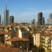 Affitti Milano, panorama con tetti in cotto e grattacieli moderni sotto un cielo azzurro